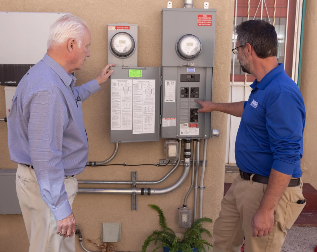 City electrical inspector and licensed electrician examining completed electrical panel upgrade installation during final inspection