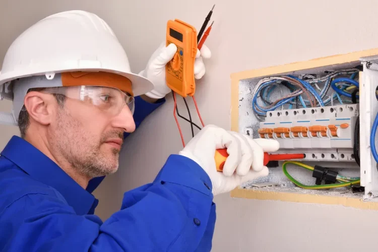 Licensed electrician examining an outdated electrical panel with open door showing circuit breakers and wiring connections