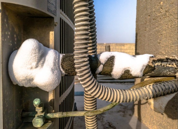 Frozen evaporator coils with ice formation showing signs of refrigerant leak requiring emergency air conditioning repair