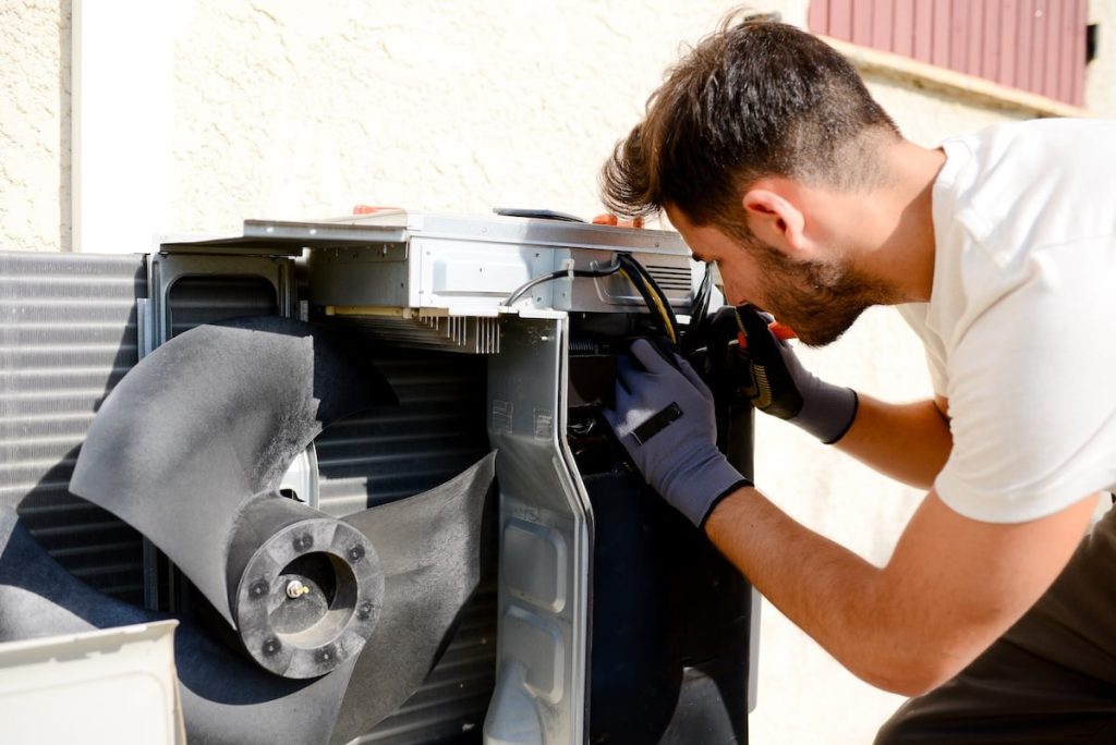 Professional HVAC technician diagnosing air conditioner emergency during urgent repair service call - HVAC And Electric Services | Arc Electric Professional HVAC technician diagnosing air conditioner emergency during urgent repair service call